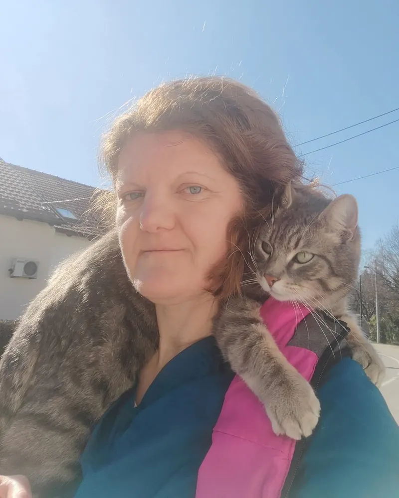 Ines Petrović, dr. med. vet., u radnoj odori s mačkom na ramenu ispred ambulante